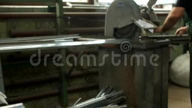 工人在一个圆锯、圆锯和金属型材上切割一个PVC窗户的金属型材